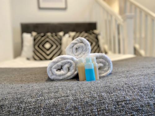 a glass of juice and towels on a bed at Luxeurs - Victoria Street Apartments in Liverpool