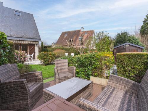 un patio avec des chaises en osier et une table dans l'établissement Holiday Home Le Pré Verger-1 by Interhome, à Villers-sur-Mer