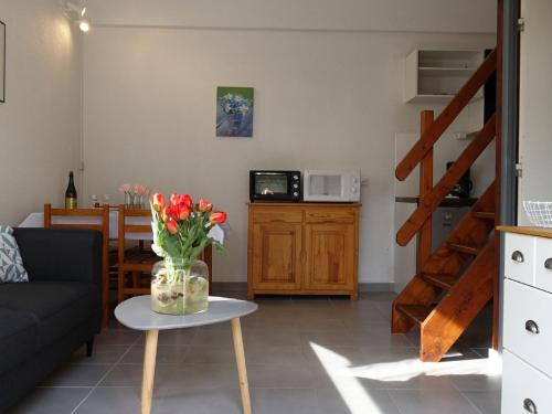 a living room with a table with a vase of flowers at Holiday Home Les Charmilles-6 by Interhome in La Palmyre