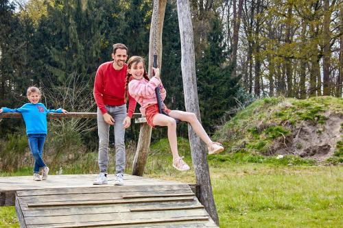 a man and a woman and a child on a wooden bridge at Green Resort Limburg in Houthalen-Helchteren