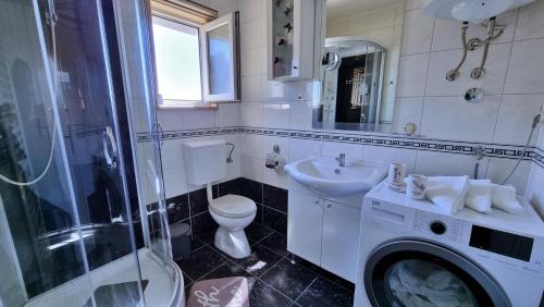 a bathroom with a toilet sink and a washing machine at Black and White Apartment - 2 bedrooms, walk to the beach in Duće
