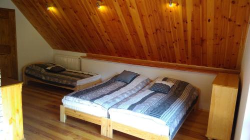 een slaapkamer met 2 bedden in een kamer met houten wanden bij Cztery Pory Lasu 