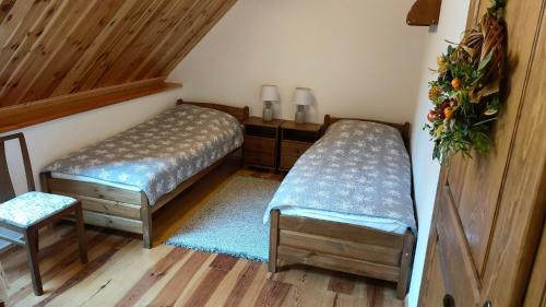 Dos camas individuales en una habitación con suelo de madera. en Cztery Pory Lasu, en Silna Nowa