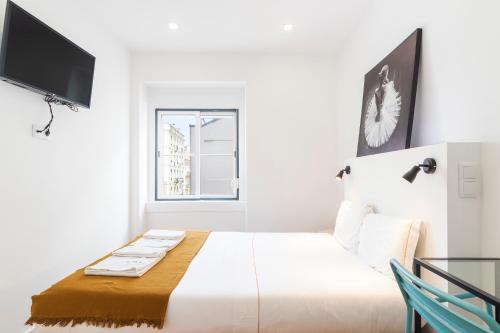a white bedroom with a large bed and a window at Gloria 10 in Lisbon