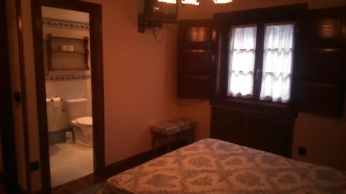 a bathroom with a window and a toilet and a mirror at Casa Rural La Huerta in Riaño