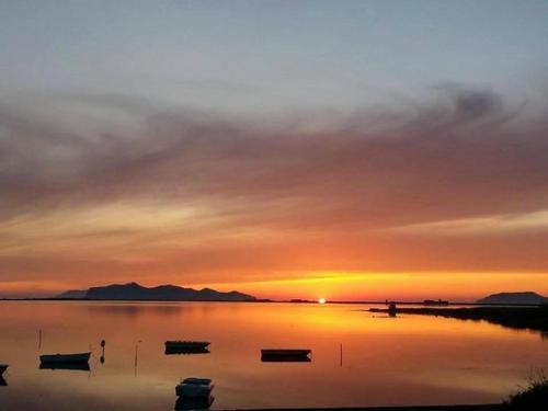 una puesta de sol sobre un lago con barcos en el agua en ZEFIRO, en Marsala