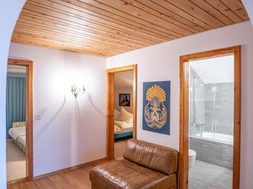 a living room with a leather chair and a bathroom at Apartment Chesa La Sajetta 12 by Interhome in Surlej
