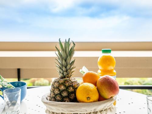 eine Schale Obst mit einer Ananas und einer Flasche Saft in der Unterkunft Apartment Les Terrasses du Levant-5 by Interhome in Canet-en-Roussillon