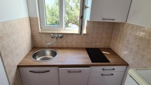 una pequeña cocina con fregadero y ventana en Apartments Kust, en Mlini