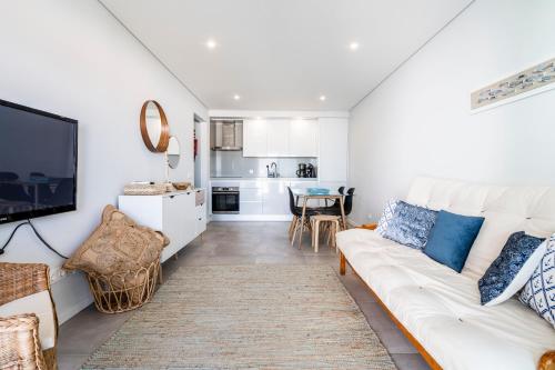 uma sala de estar com um sofá branco e uma cozinha em Coastal Holiday´s Apartment em Monte Gordo