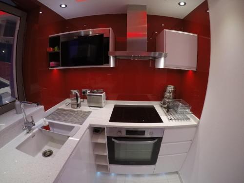 - une cuisine avec des murs rouges et une cuisinière four supérieur dans l'établissement Perfect Central London Base, à Londres