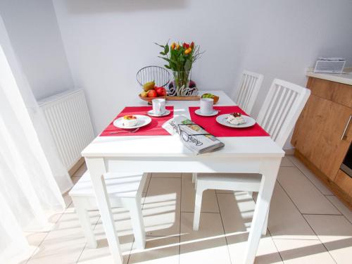 einen weißen Tisch mit zwei weißen Stühlen und einem roten Tischtuch in der Unterkunft Apartment Küstenoase by Interhome in Norddeich