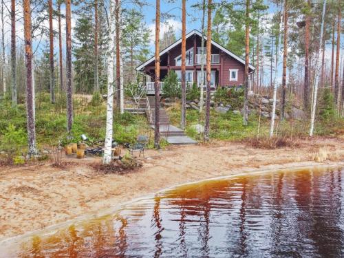 a house in the woods next to a body of water at Holiday Home Loisteranta by Interhome in Vääräkoski