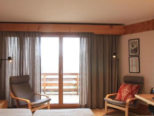 Habitación con 1 cama, 2 sillas y balcón. en Studio Le Bristol B36 by Interhome, en Villars-sur-Ollon