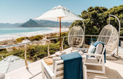 a deck with chairs and an umbrella and the beach at Last Word Long Beach in Kommetjie