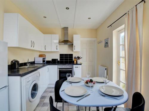 uma cozinha com uma mesa e cadeiras com copos de vinho em Holiday Home Eglos by Interhome em Saint Merryn