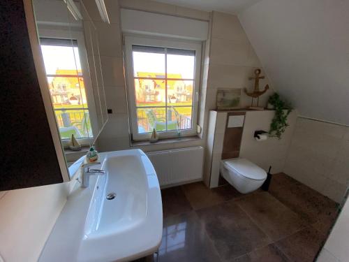 La salle de bains est pourvue d'un lavabo, de toilettes et de 2 fenêtres. dans l'établissement HUUS ANT DEEP OG, à Krummhörn