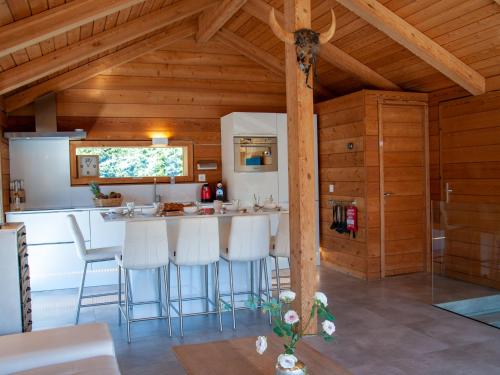 a kitchen with a bar with white stools at Chalet Papillon by Interhome in Nendaz