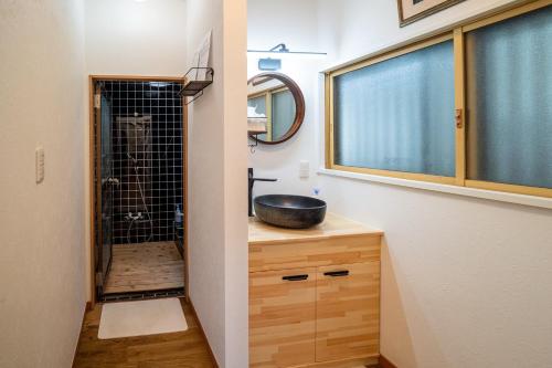 ein Badezimmer mit einem Waschbecken und einem Hund in der Dusche in der Unterkunft Immaculate Private Family Cottage with Hot Spring in Towada