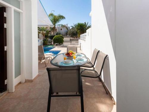 a glass table and chairs on a balcony with a pool at Villa elsa by Interhome in Protaras