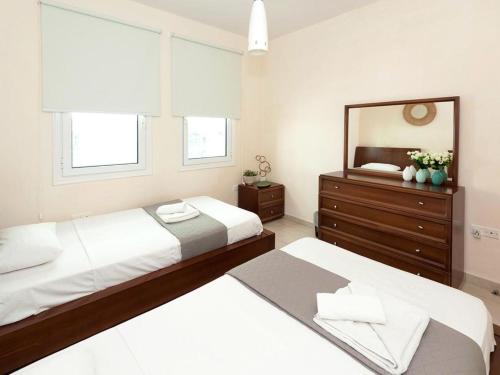 two beds in a bedroom with a mirror and a dresser at Villa elsa by Interhome in Protaras