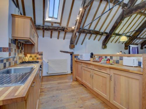 a large kitchen with wooden cabinets and wooden floors at Holiday Home Pa by Interhome in Machynlleth