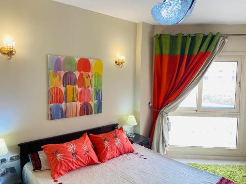 艾因蘇赫納的住宿－Porto sokhna pyramids - family only，一间卧室配有一张带红色枕头的床和一扇窗户