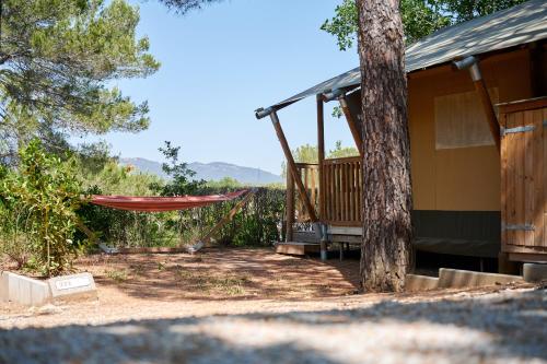 a hammock in front of a house with a tree at Glamping Frejus in Roquebrune-sur-Argens