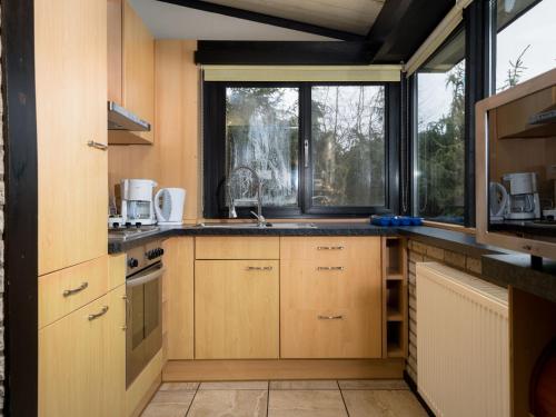 una cocina con armarios de madera y una gran ventana en Holiday Home Waldferienpark Gerolstein-6 by Interhome en Gerolstein