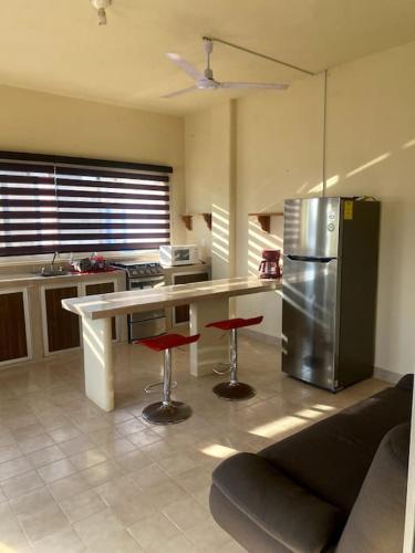 a kitchen with a counter with stools and a refrigerator at Bungalow at the beach all services in Rincon de Guayabitos