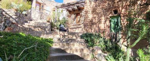 - un bâtiment en pierre avec des escaliers menant à une porte verte dans l'établissement Pacha Cuty Hostel, à Amaichá del Valle