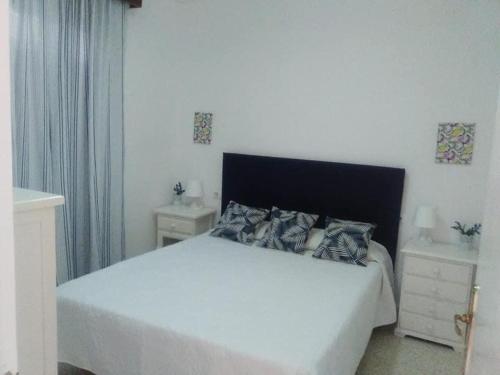 a bedroom with a white bed and two night stands at UNIFAMILIAR SIERRA DE CADIZ in El Bosque