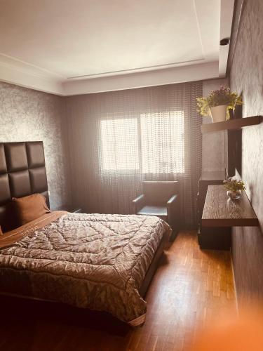 a bedroom with a bed and a table and a window at Deluxe apartments in Casablanca