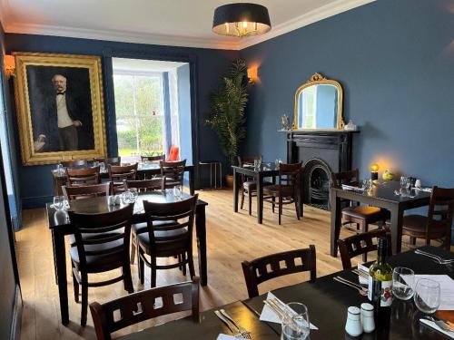 a restaurant with tables and chairs and a portrait of a man at Picton-House in St Clears