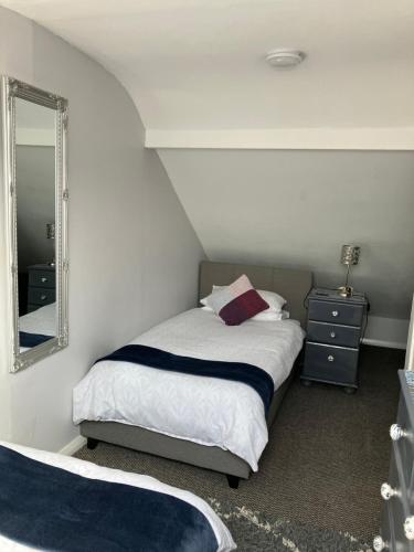 ein kleines Schlafzimmer mit einem Bett und einem Spiegel in der Unterkunft Causeway Street Holiday House Self Catering-Portrush in Portrush