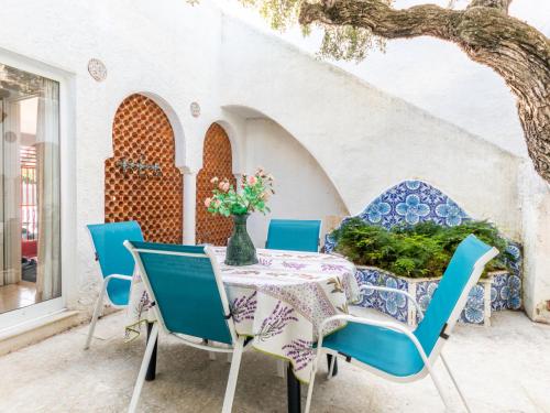 einen Tisch mit blauen Stühlen und eine Vase mit Blumen darauf in der Unterkunft Holiday Home Los Abuelos by Interhome in Cambrils