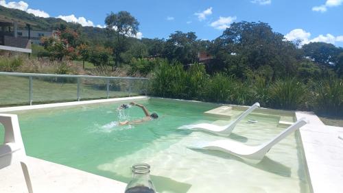 un hombre está en una piscina con dos sillas en HERMOSA CASA CAMPO, EL MEJOR PAISAJE DE SALTA en Salta