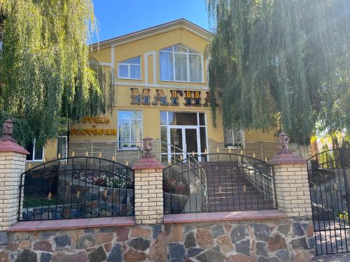 a yellow building with a gate in front of it at Готель МАГНАТ in Sutysky