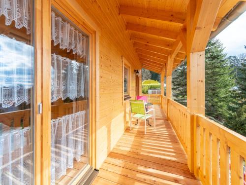 une terrasse couverte d'une maison en bois avec une chaise verte dans l'établissement Holiday Home Chalet Toni mit Sauna by Interhome, à Spiegelau