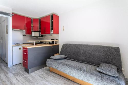 een keuken met rode kasten en een bank in een kamer bij Les Alpages de Vars - maeva Home in Vars