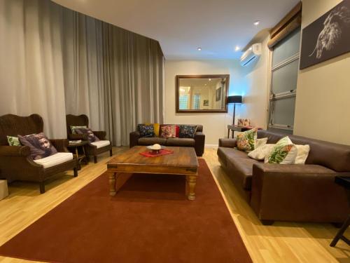 a living room with couches and a coffee table at Imany Guest House in Bloubergstrand