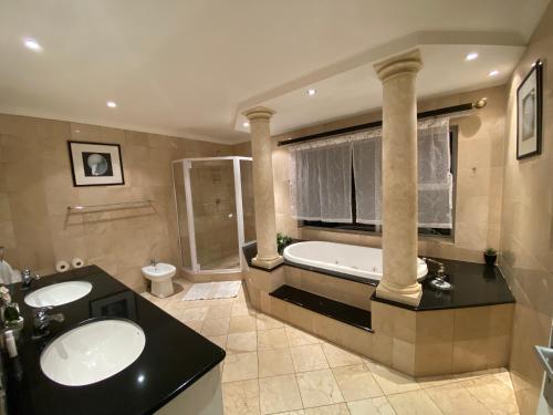 La salle de bains est pourvue de 2 lavabos et d'une baignoire. dans l'établissement Imany Guest House, à Bloubergstrand
