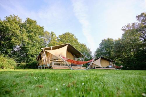 ein Gebäude mit einer Hängematte und Zelten auf einem Feld in der Unterkunft Glamping Twente in Denekamp