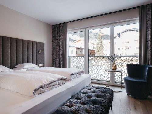a bedroom with two beds and a large window at Hotel Chesa Monte 4Sterne Superior in Fiss