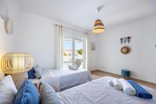 um quarto com 2 camas, um sofá e uma janela em Casa Melancia na Praia da Luz