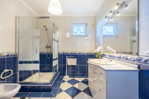 uma casa de banho azul e branca com um chuveiro e um lavatório. em Casa Melancia na Praia da Luz