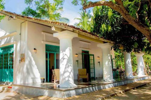 a white house with columns and a tree at Mawella House 1807, Tangalle in Tangalle