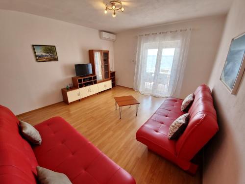 a living room with a red couch and a table at Apartments Cacija in Trogir
