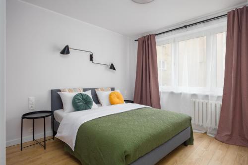 a bedroom with a bed with a green blanket and a window at Śródmieście Homely Apartment in Warsaw