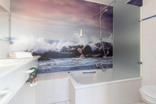 ein Badezimmer mit einem Bild einer abstürzenden Welle in der Unterkunft Fletcher Badhotel Callantsoog in Callantsoog